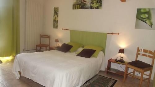 a bedroom with a large white bed and two chairs at Chambres d'hôtes- Le Pré aux Ânes in Albon