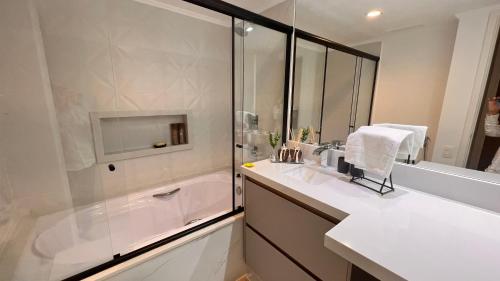 ein weißes Bad mit einer Dusche und einem Waschbecken in der Unterkunft Flat Ninety Jardins próximo Pq do Ibirapuera - SP in São Paulo