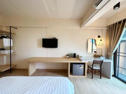 a bedroom with a desk with a tv and a bed at I-Home Residence and Hotel in Pluak Daeng