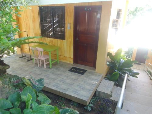 a porch with a table and a wooden door at Woodland Inn in El Nido