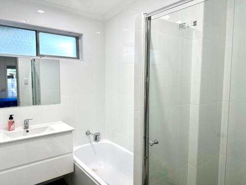 a white bathroom with a shower and a sink at Grabber- Three bedroom charm in Alice Springs in Alice Springs