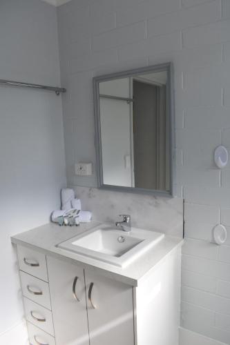 a white bathroom with a sink and a mirror at Crystal Waters 7 in Bargara