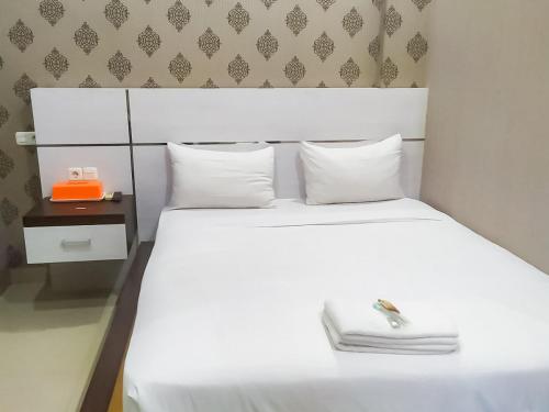 - une chambre avec un grand lit blanc et une table de chevet dans l'établissement RedDoorz Syariah near Sultan Syarif Kasim II Airport, à Pekanbaru