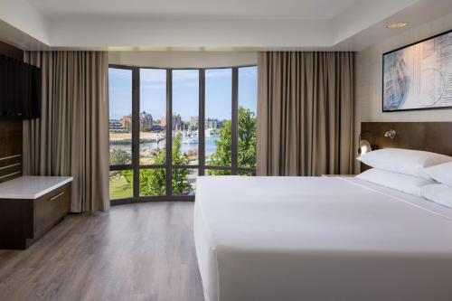 a hotel room with a large bed and a large window at Delta Hotels by Marriott Victoria Ocean Pointe Resort in Victoria