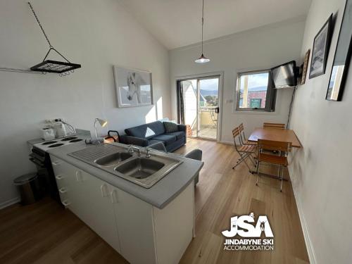 a kitchen with a sink and a living room at Razorback 3 in Jindabyne