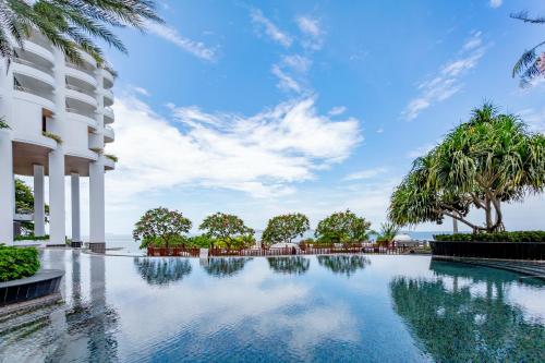 a swimming pool at a resort with palm trees at Royal Cliff Grand Hotel Pattaya in Pattaya South