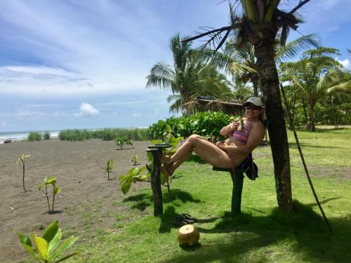a woman sitting on a bench on the beach at Villas Playa Palo Seco in Parrita