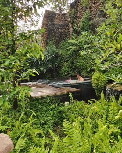 a person in a bath tub in a garden at Rarin Villas in Chiang Mai