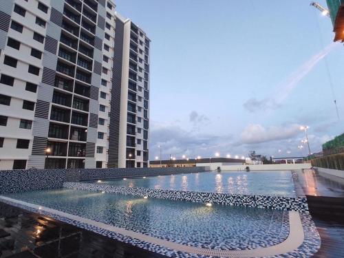 a large swimming pool in front of two tall buildings at MAI Desaru Utama Residence in Bandar Penawar