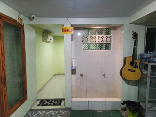a bathroom with a shower with a guitar on the wall at Balqies Homestay Syariah Makassar Mitra RedDoorz in Makassar