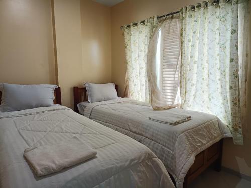 two beds in a room with a window at Balqies Homestay Syariah Makassar Mitra RedDoorz in Makassar
