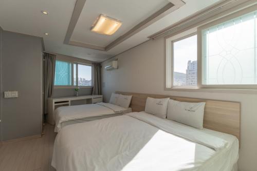 two beds in a room with two windows at Staywell Hotel in Busan