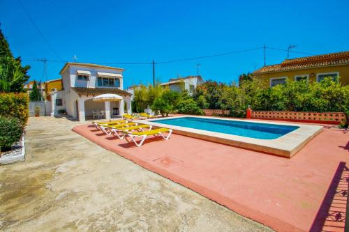 una piscina con sillas, una mesa y una casa en Tere - holiday home with private swimming pool in Calpe en Calpe