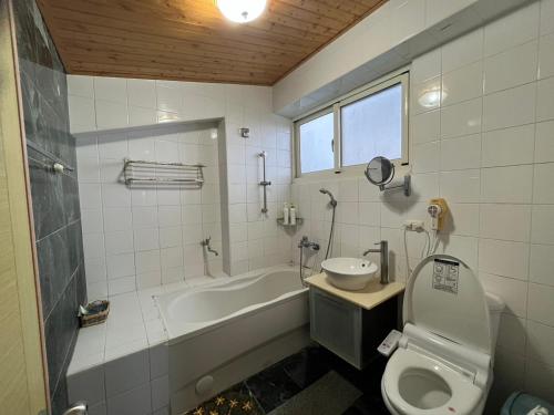 a bathroom with a tub and a toilet and a sink at Hualien Bay in Ji'an