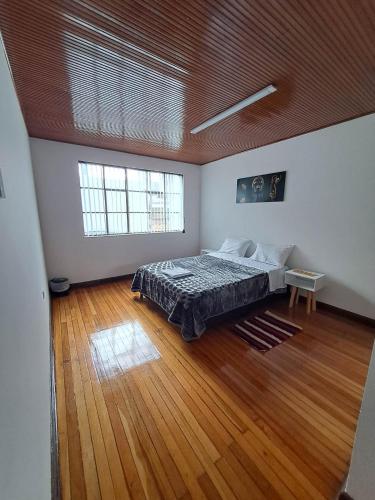 duża sypialnia z łóżkiem i drewnianą podłogą w obiekcie Makarena Hostel w mieście Bogota
