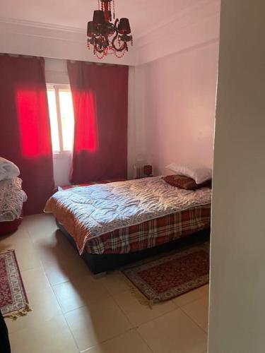 a bedroom with a bed with red curtains and a window at appartement dans résidence Marrakech avec piscine in Marrakesh