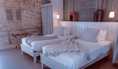 a bedroom with two beds with white sheets at Sandy Bay in Nusa Lembongan