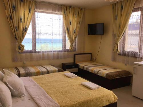 a bedroom with two beds and a tv and windows at Ivanka Guest House in Obzor