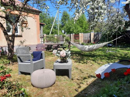 a hammock in a yard with a chair and a table at Cozy private house with a yard & parking in Rīga