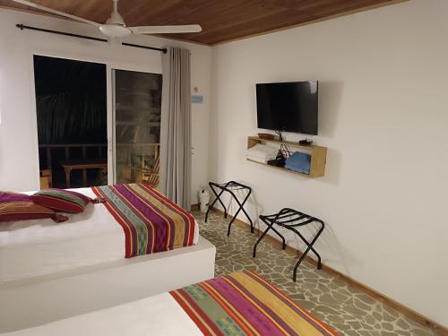 a bedroom with a bed and a tv on the wall at Hotel Casa Sattva- Bed & Breakfast in Rincón