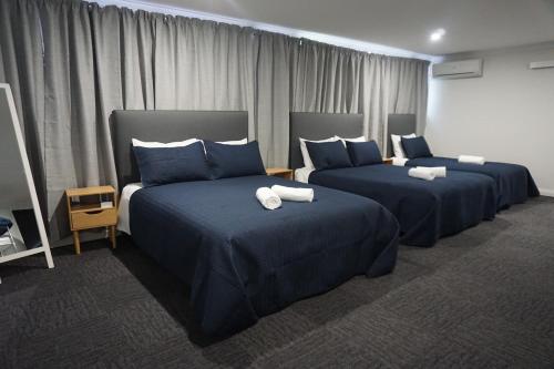a hotel room with two beds with blue sheets at Warners Bay Hotel in Warners Bay