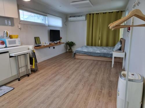 a room with a bedroom with a bed and a microwave at Cozy House & Tour in Jeju