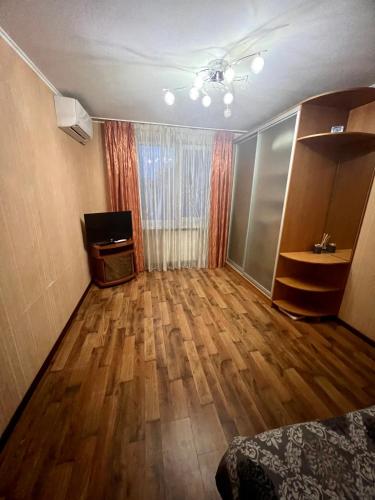 an empty room with a wooden floor and a television at Квартира на березі Дніпра у новому будинку! in Cherkasy