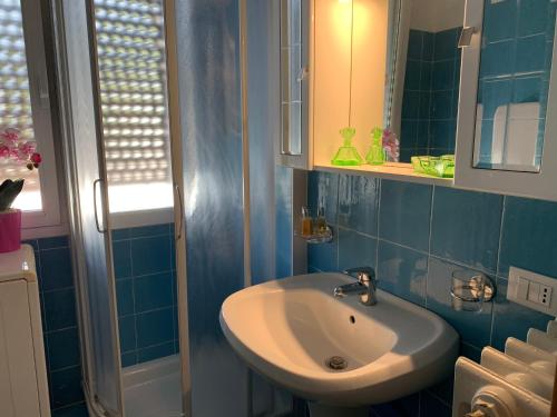a blue tiled bathroom with a sink and a mirror at Palazzina Salodium INCANTO - ARMONIA - ENERGIA in Salò