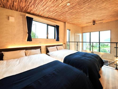 two beds in a room with two windows at Rakuten STAY VILLA Lake Yamanakako 101 View bath Mt Fuji View in Yamanakako