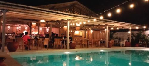 a group of people sitting at a restaurant next to a pool at Bungalow Cafe Gili Beachfront in Gili Meno