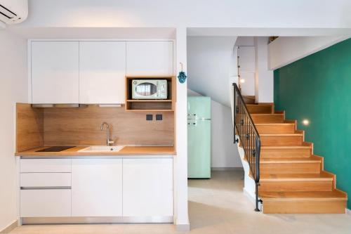a kitchen with white cabinets and a staircase at Aerino Luxury Villas in Chrysi Ammoudia