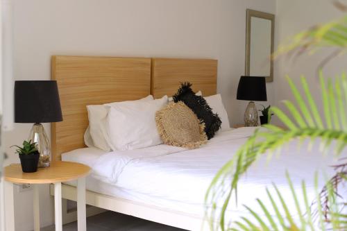 a bed with white sheets and pillows and a table at Sea Green Boutique Rooms in General Luna