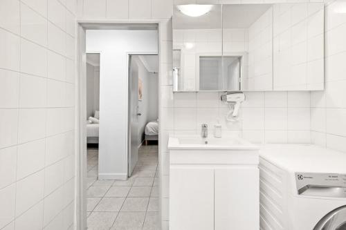 a white bathroom with a sink and a washing machine at Signature Double Room in Auburn in Sydney