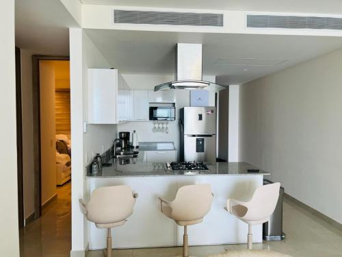 a kitchen with white appliances and white chairs at Camino al Mar in Mazatlán