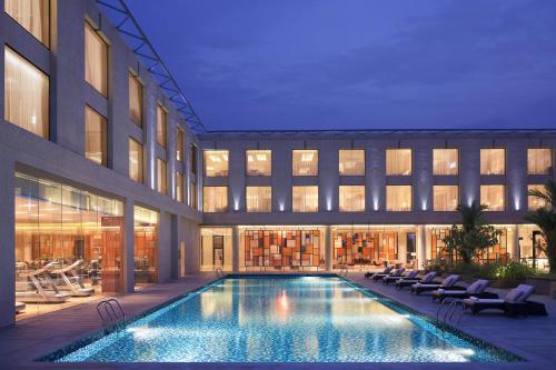 a hotel with a swimming pool in front of a building at Courtyard by Marriott Kochi Airport in Nedumbassery