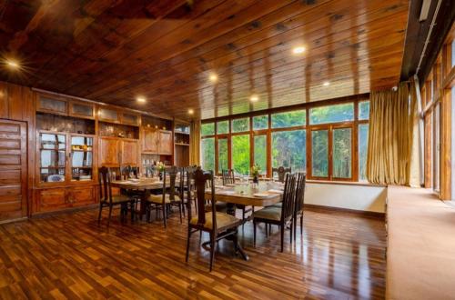 Ramgarh Heritage Villa, Manali, amã Stays & Trails في مانالي: غرفة طعام كبيرة مع طاولات وكراسي ونوافذ