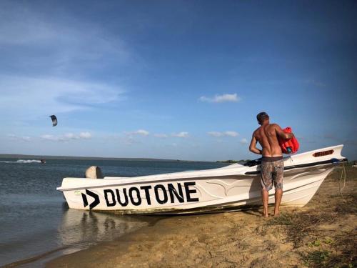 a man standing next to a boat on a beach at Anawasal in Kalpitiya