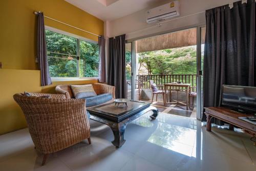 ein Wohnzimmer mit einem Sofa und einem Tisch in der Unterkunft Good Time Sports Village Koh Mak in Ko Mak
