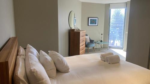 a bedroom with a bed with white pillows and a mirror at A Window on the Bay in Metung