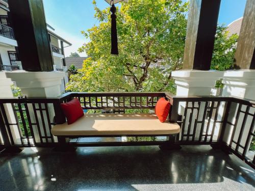 a bench on a porch with two pillows on it at Thai Akara - Lanna Boutique Hotel in Chiang Mai