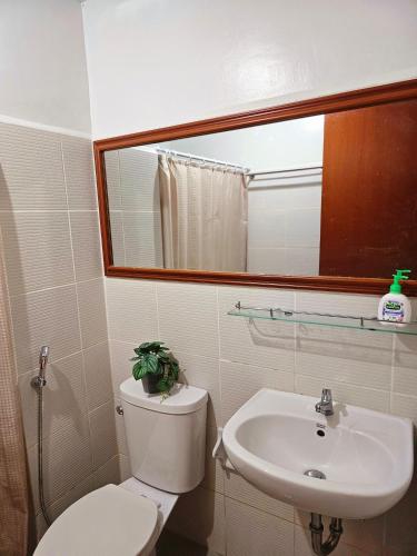 a bathroom with a toilet and a sink and a mirror at JETS'3 Condo Rentals in Bacolod
