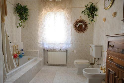 a bathroom with a toilet and a tub and a window at Villa per gruppi fino a 20 persone, con piscina privata, camino e grande giardino nelle colline marchigiane in Pian di Mulino