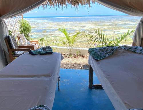 two beds in a room with a view of the ocean at Lala Land Lodge in Kizimkazi