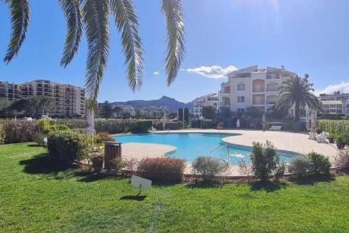 uma piscina num quintal com palmeiras em Cannes Marina vue sur le port em Mandelieu-la-Napoule