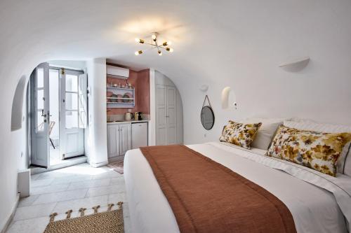 イメロヴィグリにあるEl Verano Hideawayの白いベッドルーム(大型ベッド1台付)、キッチンが備わります。