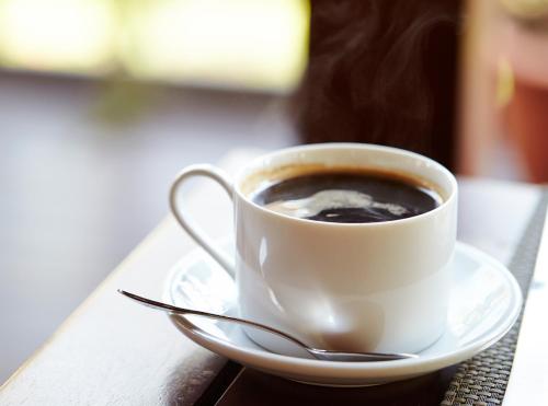 a cup of coffee on a plate on a table at La Vista Patong Hotel in Patong Beach