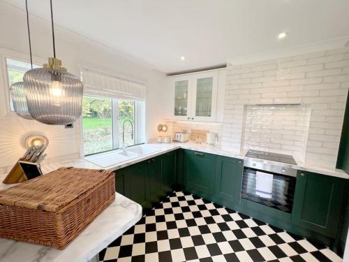 a kitchen with green cabinets and a checkered floor at Magnolia Cottage - Kent in Lyminge