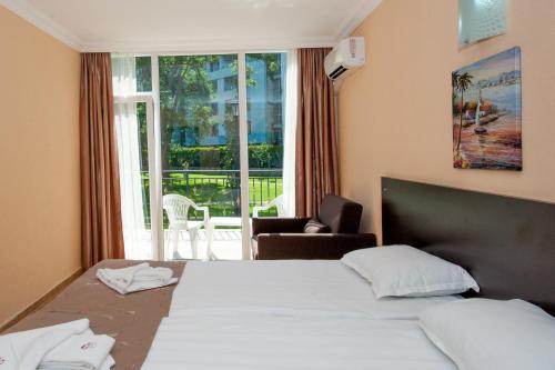 サニービーチにあるHotel Riva - All Inclusiveのベッドと大きな窓が備わるホテルルームです。