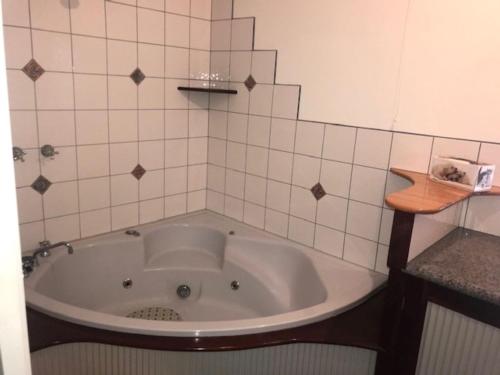 een badkamer met een bad en witte tegels bij 51 Grossard Point Road in Ventnor