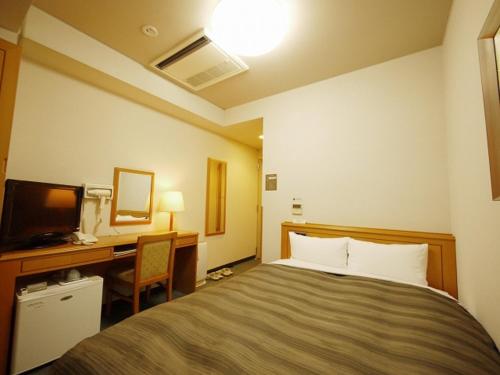 una camera d'albergo con letto e scrivania di Hotel Route-Inn Shin-Shirakawa Eki Higashi a Shirakawa